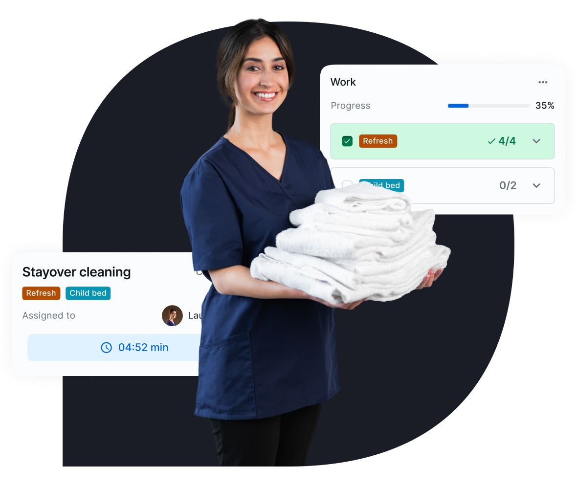 Smiling housekeeping staff member in a navy uniform holding a stack of folded white towels, with a task management interface overlay showing 'Stayover cleaning' with Refresh and Cild bed label, and 'Cleaning checklist'