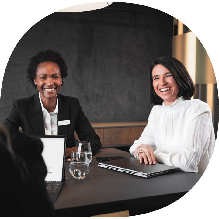 Two ladies smiling while sitting in a meeting